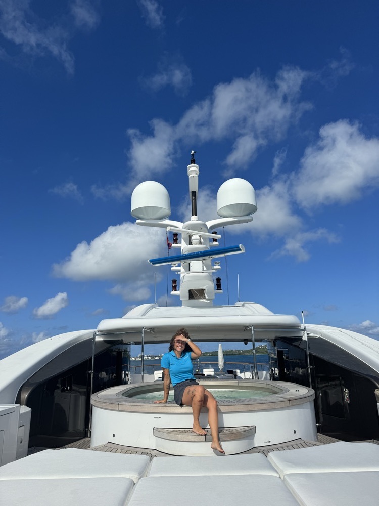 Bárbara no deck superior de um superyacht, com céu azul ao fundo