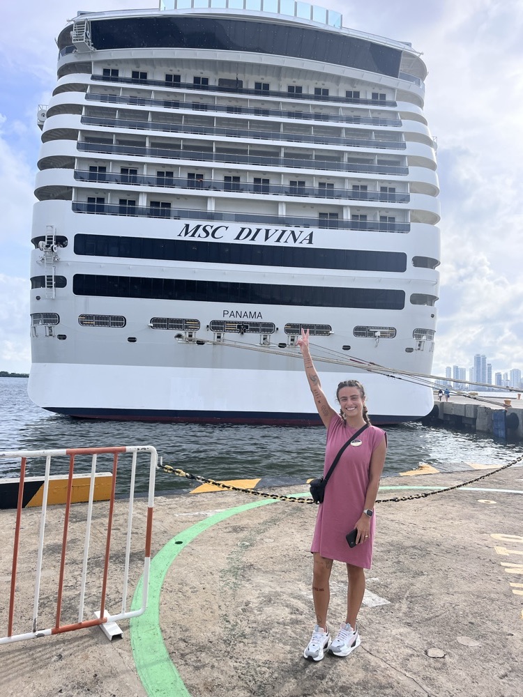 Bárbara acenando em frente ao navio MSC Divina, atracado no porto