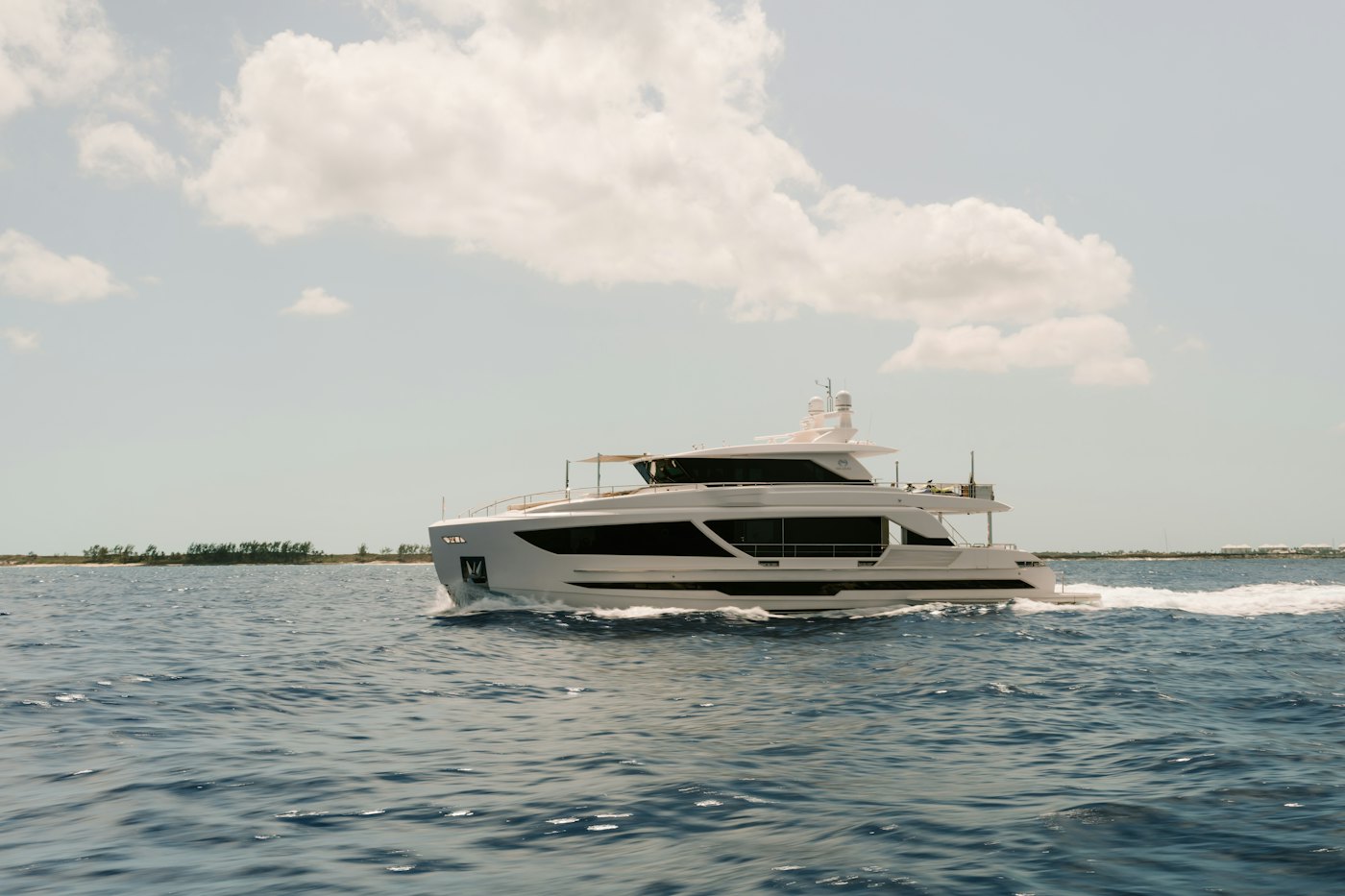 Superyacht branco ancorado em águas azuis, com montanhas ao fundo
